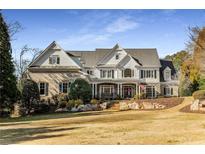 Beautiful two-story brick home with manicured lawn, stone accents, and a covered front porch at 12710 Old Surrey Pl, Roswell, GA 30075