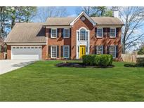 Charming two-story brick home with a manicured lawn and a bright yellow front door at 780 Hounds Ridge Ct, Lawrenceville, GA 30043