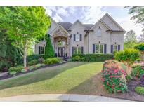 Charming two-story home featuring a well-manicured lawn, lush landscaping, and a stone-accented entrance at 2400 Weber Heights Way, Buford, GA 30519