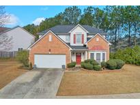 Charming two-story brick home featuring a well-manicured lawn, attached two-car garage, and inviting red front door at 3466 Northfield Nw Way, Kennesaw, GA 30144