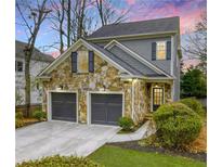 Charming two-story home featuring a stone facade and a two-car garage with grey doors at 1048 Standard Ne Dr, Atlanta, GA 30319