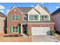 Two-story brick home featuring green shutters, a white garage door, and manicured landscaping at 5819 Rue Chase Way, Tucker, GA 30084