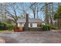 Charming home featuring a brick chimney, quaint porch, and light-colored exterior, nestled in a wooded lot at 1849 S Columbia Place, Decatur, GA 30032