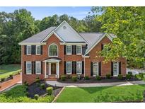 Beautiful two-story red brick home with mature landscaping, black shutters, and a welcoming front entrance at 4780 Woodruff Trce, Cumming, GA 30028