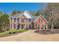 Charming two-story red brick home with black shutters and a well-manicured lawn and landscaped front yard at 4780 Woodruff Trce, Cumming, GA 30028