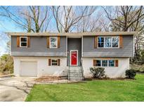 Charming split-level home with a red front door, wood accents, and fresh landscaping at 2330 Lago Dr, Jonesboro, GA 30236