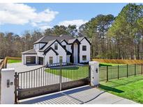 Stunning two-story home with a gated entrance, black trim, a three-car garage and a landscaped yard at 3057 Bold Springs Rd, Dacula, GA 30019