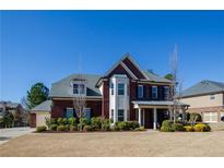 Charming brick two-story home featuring a manicured lawn, mature landscaping, and a welcoming front porch at 2480 Copper Mill Trl, Cumming, GA 30041