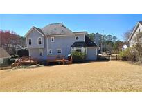 Spacious backyard featuring a large grassy area, wooden deck, privacy fence, and mature trees, perfect for outdoor activities at 4905 Puritan Dr, Sugar Hill, GA 30518
