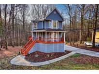 Charming two-story home featuring a welcoming porch and freshly painted stairs surrounded by a lush, wooded landscape at 1310 Ridgeview Rd, Auburn, GA 30011