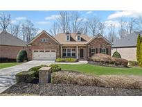 Charming brick home with a well-manicured lawn, complemented by a two-car garage and mature trees at 4930 Cecilia Sq, Cumming, GA 30040