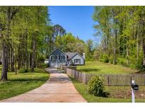 Charming single-Gathering home featuring a long driveway and a beautifully landscaped front yard with mature trees at 5570 Rolling Oaks Dr, Cumming, GA 30040
