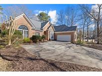 Charming brick home featuring a large driveway, two-car garage, and meticulously landscaped front yard at 8424 Fairway Dr, Covington, GA 30014