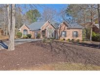 Charming brick home features a well-manicured lawn, mature trees, and a circular driveway at 8424 Fairway Dr, Covington, GA 30014