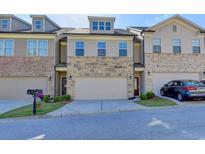 Charming townhome with a two-car garage and stone accents on the facade at 3082 Cedar Glade Ne Ln, Buford, GA 30519