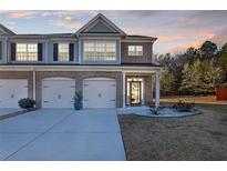 Charming townhome features a brick facade, attached garages, and a well-manicured lawn at dusk at 7207 Brigidoon Rose, Douglasville, GA 30134