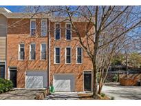 Charming brick townhome featuring attached garages and well-maintained landscaping at 651 Park Village Ne Dr, Atlanta, GA 30306