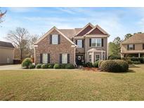 Charming two-story home featuring a well-manicured lawn and a mix of brick and siding accents at 5156 Olive Branch Cir, Powder Springs, GA 30127