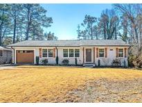 Charming home with white brick, wood shutters, well-manicured landscaping, and a neatly kept lawn at , Tucker, GA 30084