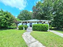 Exterior view of damaged single story home with overgrown yard and debris at 2022 Cook Rd, Decatur, GA 30032