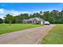 Beautiful brick home with a well-manicured lawn, long driveway, and mature trees at 501 Barhams Dr, Mcdonough, GA 30252