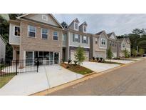 Row of modern townhomes with brick and siding exteriors with driveways and landscaping on a cloudy day at 4353 Morning Vw, Stone Mountain, GA 30083