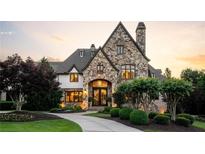 Spectacular stone home featuring a custom circular driveway and lush landscaping at 938 Crescent River Pass, Suwanee, GA 30024