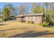 Charming brick home featuring a well-maintained lawn and covered front porch entry at 928 Magna Carta Nw Dr, Atlanta, GA 30318