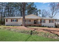 Charming white brick home featuring a cozy front porch and well-manicured lawn at 2681 Beckwith Se Trl, Marietta, GA 30068
