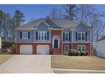 Charming two-story home featuring a brick facade, light blue siding, manicured lawn and attached two-car garage at 1772 Ascot Nw Run, Acworth, GA 30102
