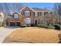 Beautiful brick two-story home featuring a well-manicured lawn, attached garage, and classic architectural details at 407 Spring House Ne Cv, Atlanta, GA 30307