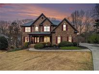 Beautiful two-story brick home with manicured landscaping and a welcoming covered front porch at 6350 Old Wood Hollow Way, Buford, GA 30518