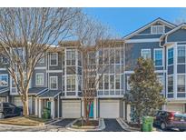 Charming townhomes boast large windows, attached garages, and vibrant turquoise doors, set against a backdrop of mature trees and blue skies at 1059 Park Row North Se, Atlanta, GA 30312