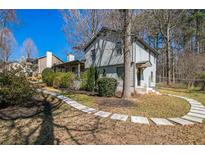 Charming home with a landscaped yard, stone walkway, and mature trees on a sunny day at 700 Hill Meadow Dr, Dacula, GA 30019