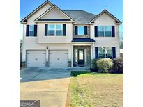 Charming two-story home featuring a brick entryway, two-car garage, and well-manicured lawn at 611 Winners Cir, Locust Grove, GA 30248