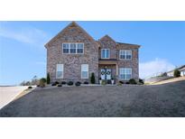 Two-story brick home featuring a well-manicured front lawn and charming architectural details at 1604 Falcon Ct, Locust Grove, GA 30248