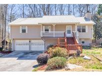 Charming split-level home with metal roof, front porch, deck, and two-car garage at 3016 Ansley Manor Ct, Snellville, GA 30078