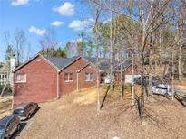 Charming brick home with an attached garage, surrounded by trees and a partially sunny sky at 114 N Springs Way, Acworth, GA 30101