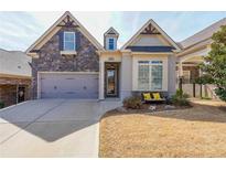 Charming home exterior with stone accents, a well-manicured lawn, and a welcoming front entrance at 307 Serenity Way, Woodstock, GA 30188