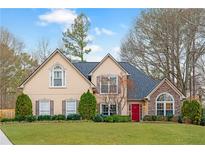 Charming two-story home with manicured lawn, a red door, and a mix of stone and siding accents at 4910 Hunters Oaks Ln, Alpharetta, GA 30009