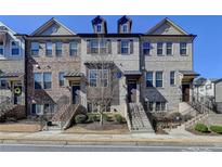 Charming townhome featuring a brick facade, landscaped front yard, and inviting entrance steps at 4498 Dunblane Ave, Sugar Hill, GA 30518