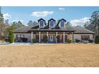 Charming brick home featuring dormer windows, a pillared porch, and manicured landscaping at 1369 Sierra Ridge Pl, Loganville, GA 30052