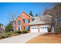 Charming two-story red brick home featuring a two-car garage and well-manicured landscaping at 1439 Evers Pl, Lawrenceville, GA 30043