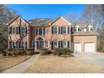 Traditional brick two-story home with black shutters, manicured landscaping, and attached two-car garage at 2050 Federal Rd, Roswell, GA 30075