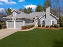 Charming gray home with a two-car garage, stone accents, and manicured lawn at , Woodstock, GA 30189