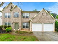 Beautiful brick home featuring a well-manicured lawn, mature landscaping, and a two-car garage at 1761 Brandemere Dr, Austell, GA 30168