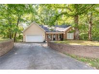 Charming single-story home featuring a brick facade, attached garage, and lush landscaping at 2208 Clarendon Ne Ct, Conyers, GA 30012