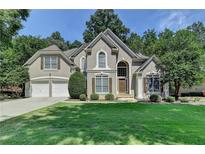 Charming two-story home with a manicured front lawn, two-car garage, and decorative shutters at 4260 River Club Dr, Cumming, GA 30041