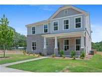 Beautiful two-story home features a brick facade, covered porch, and manicured lawn at 3387 Wild Clary Court Lot 20, Buford, GA 30519
