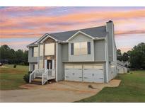 Charming two-story home featuring stone accents, gray siding, and a two-car garage against a colorful sky at 65 Randall Dr, Rockmart, GA 30153